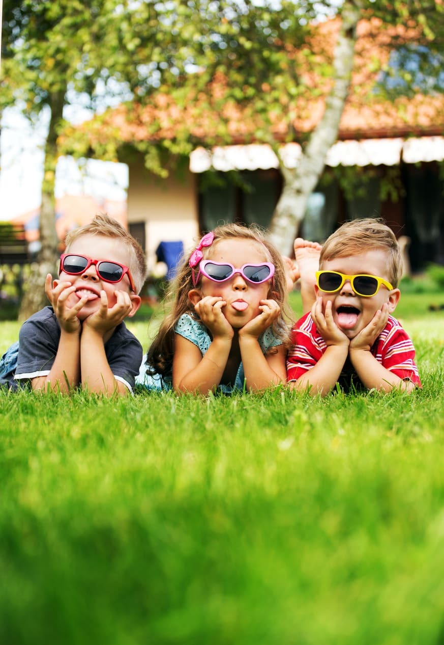 3 kinderen in het gras met een zonnebril op